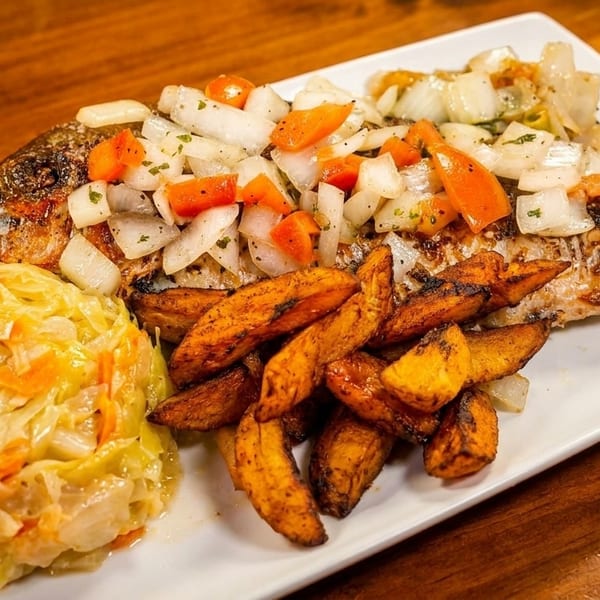 Grilled whole fish topped with onions and carrots, served with sweet potato fries and cabbage.